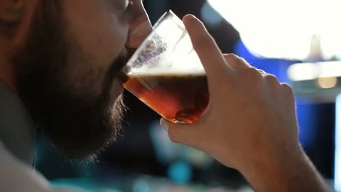 Brunette jew man drinking a dark beer in a bar.