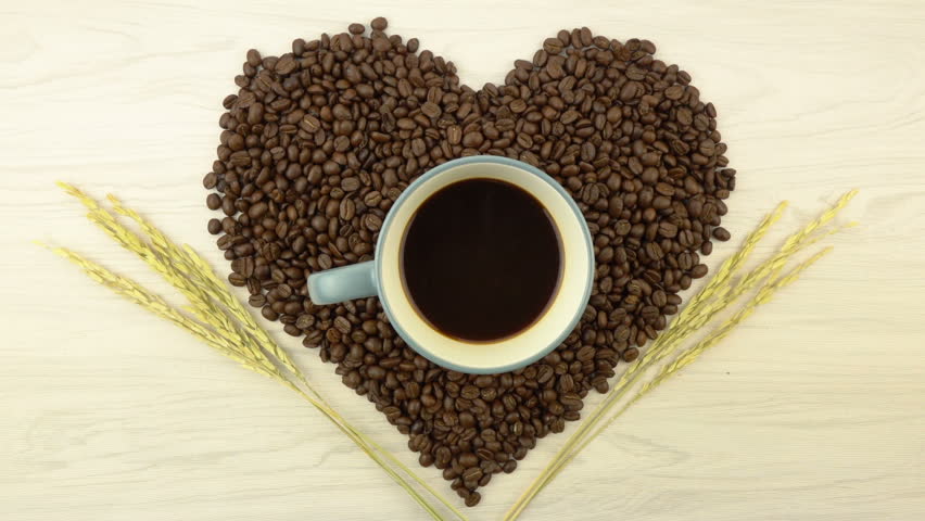 Roasted coffee beans in heart shape with coffee cup
