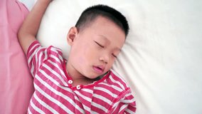 Five years old Asian boy sleeping on bed, footage video.