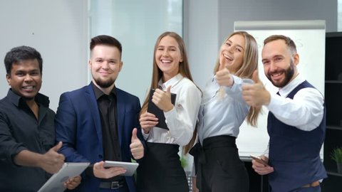 Group of smiling young multi ethnic business people enjoying and showing gesture cool thumbs up