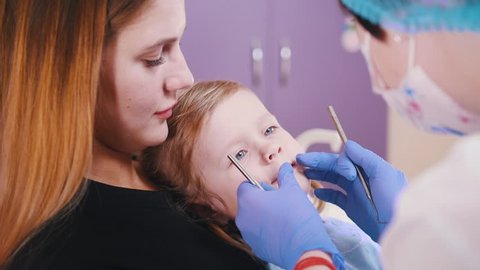Medicine, dentistry. Dentist examines opens up a little girl mouth to examine the oral cavity