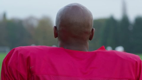 4K Portrait of smiling American football player putting on helmet and running to join the rest of his team