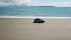 aerial video of a 4WD which is running on the beach. taken and tracked by a drone from right hand side
