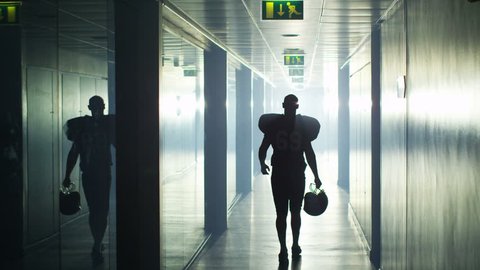 4K American football player walks alone through stadium tunnel before or after a game 库存视频