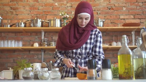Young muslim woman in kitchen cuts vegetables to cook food