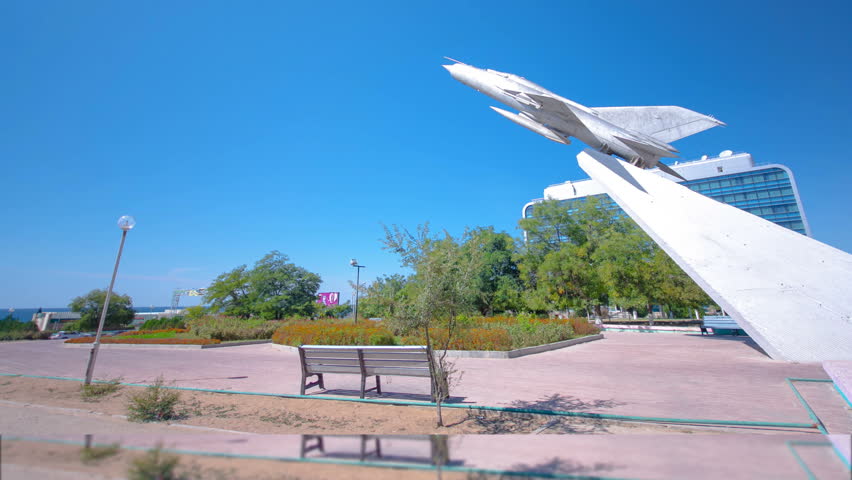 The MIG-21 plane is a monument in the square of Glory timelapse hyperlapse. Blue sky at sunny day. Aktau, Kazakhstan