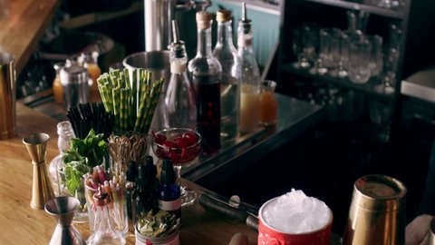 Young concentrated female bartender pouring ice into a cocktail shaker and starts shaking it in the air in interior fancy bar with soft day lighting. Close up to Medium shot on 4k RED cam on a gimbal.