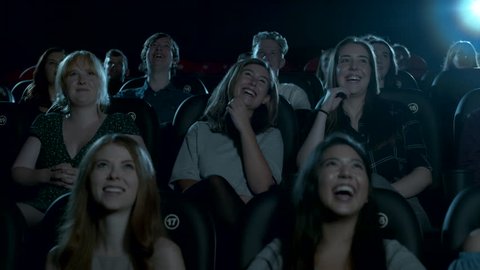 Young female movie theatre audience smiling and laughing.