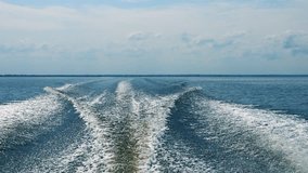 Large boat trail with foamy waves and sprays behind the fast motor boat
