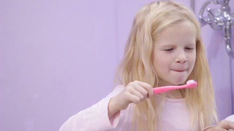 Happy blonde child kid girl laughing and brushing teeth with toothpaste. Health care, dental hygiene, people and beauty concept