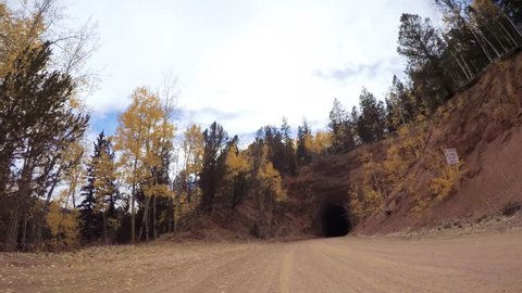 Driving through historical wood tunnel on dirt road in the mountains.