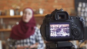 Muslim woman in hijab blogger in the kitchen preparing food in front of camera