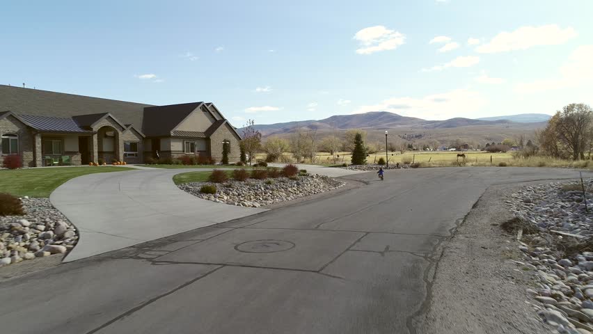 An aerial shot of a little boy riding on his bike outside