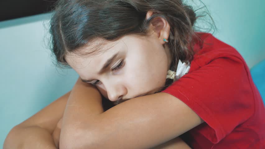 sad and depressed little girl sits sad on the bed domestic violence. girl children sad emotions. little girl experiencing lifestyle suffering concept