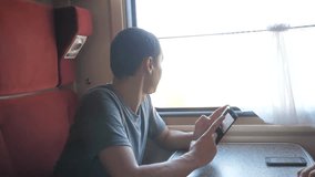 man traveler Relaxing On Train Listening To Music and smiling lifestyle through the pictures via social media. slow motion video. uploading photo using cell phone while riding home by train wagon