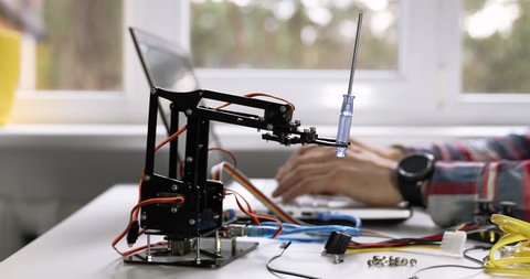 robotics engineering - technician programming robot arm on computer