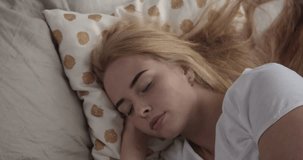 attractive girl sleeping in bed waking up and smiling at camera. Young caucasian woman stretching early in morning . 4k video footage
