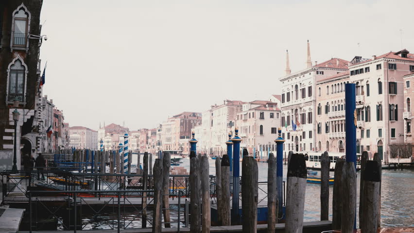 Atmospheric view of ancient architecture and beautiful wooden gondola pier on Venice street canal with boats in Italy.