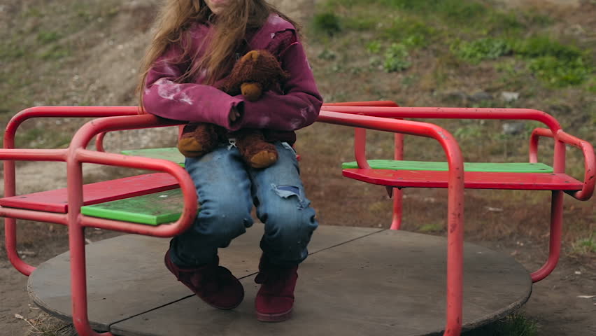 Crying sad little homeless girl whirling on the carouesel.