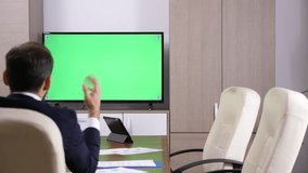 Back of businessman head talking to a green screen mock-up TV. Dolly slider 4K footage
