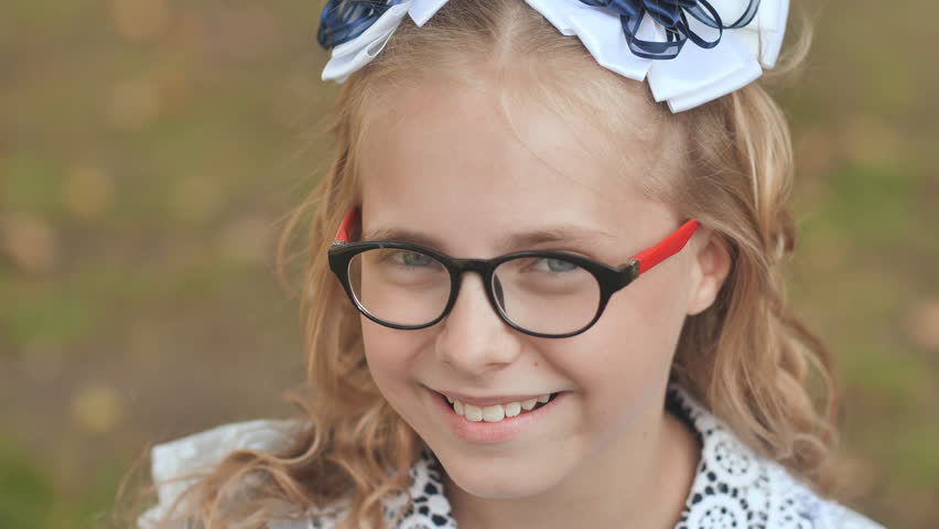 Portrait of a smiling 13 year old blonde girl pulling a bow over her head. Face close up.