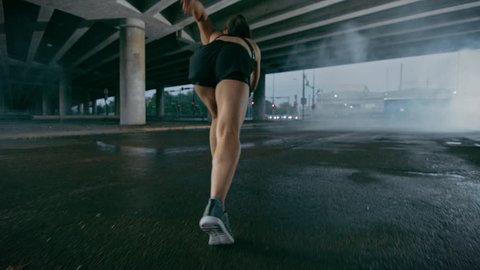 Beautiful Strong Fitness Girl in Black Athletic Top and Shorts Starts Sprinting. She is Running in an Urban Environment Under a Bridge with Cars in the Background. – Stockvideo