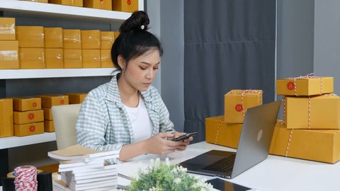 woman working and checking product order with her smartphone at home office, small online business owner