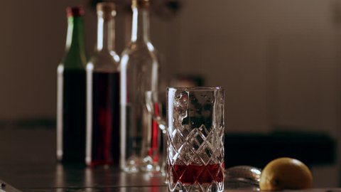 Ice cubes being placed with tongs in a tall cocktail glass in interior classy bar with soft interior lighting. Medium close up shot with shallow depth of field on 4k RED camera on a gimbal.