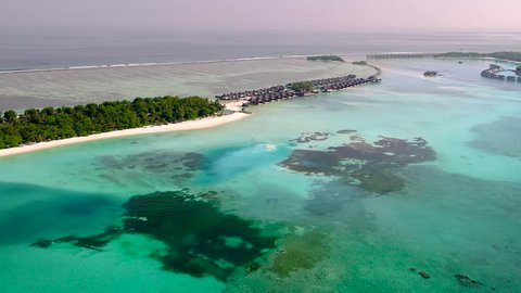 4K Top View of the Tropical Lagoon Sea Surface. Luxury 5 Star Resort Hotel. Water Bungalow hut Relaxing Holiday. Aerial Video of a Small Tropical Island in Maldives Island. Palm Tree on the Sandbank