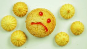 Butter biscuits with culinary paint painted with a funny emoticon and surrounded by small cookies. Movement in a circle