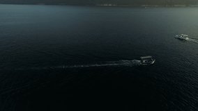 This stock footage presents an aerial shot of speed boats floating on water. The shot zooms out to reveal the rippling ocean. Use this clip as an establishing shot in movies, it comes in 4K