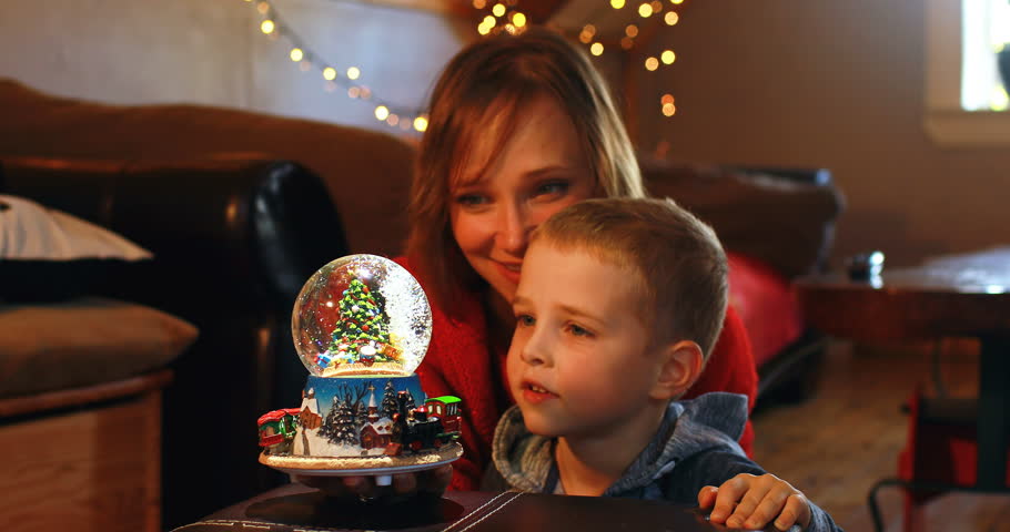 Front view close up of Caucasian mother and son playing with crystal ball toy during Christmas at home 