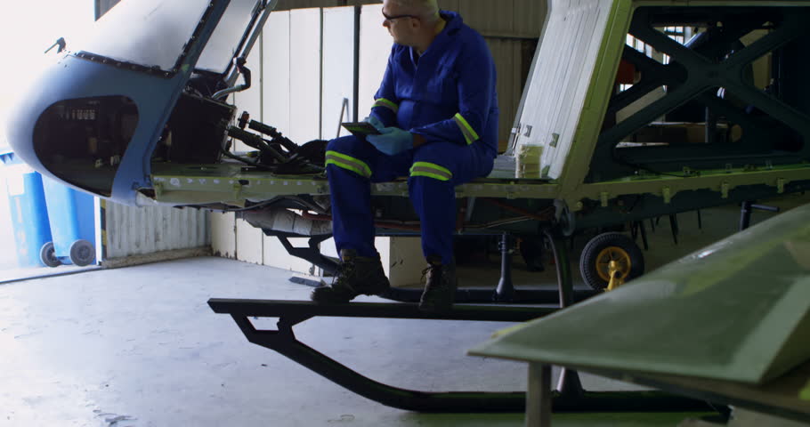 Male engineer using digital tablet in aircraft hangar