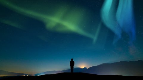 The male standing on a mountain against a sky with a northern light. time lapse