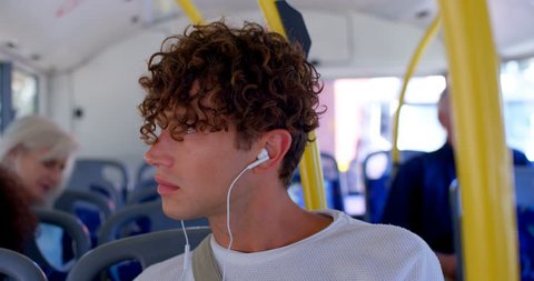 Close up of young male commuter listening music on earphones while travelling in bus