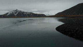 Aerial Drone Video of Iceland Landscape with bird flying over water towards mountains
