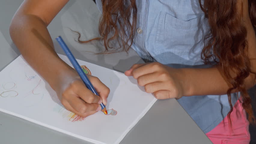 Cute red haired little girl smiling joyfully, while drawing