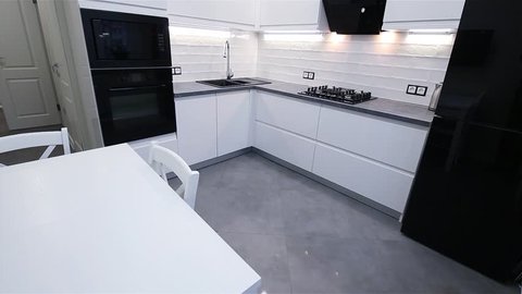 interior of a small white kitchen with built-in appliances and LED lighting.