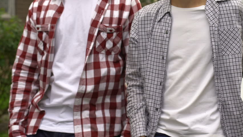 Adult man and teenager standing near car with hands crossed on chest, insurance