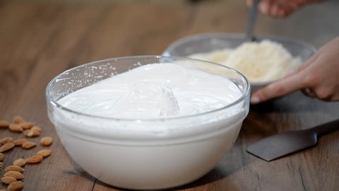 Add almond flour to the batter. Making macaron batter.
