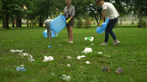Active citizens collecting garbage in public park, society against pollution