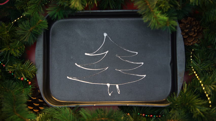 Wooden star-shape tree topper decorating drew with cream on oven tray xmas tree