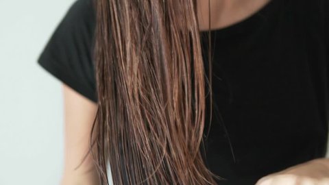 Woman slowly combing wet hair with a wooden hairbrush. She leads the comb from top to bottom. Close-up. Beautiful, healthy hair