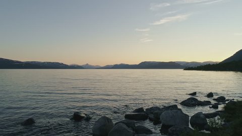 Peaceful summer night at lake Kilpisjärvi, Lapland, Finland. Mountains on the background camera tracking forward on the surface of lake. Great intro scene.