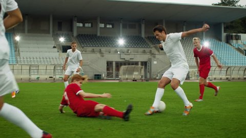 Moving Shot of Professional Soccer Player Leads with a Ball, Masterfully Dribbling and Bypassing Sliding Tackles of His Opponents. in Slow Motion.