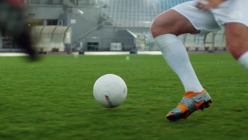 Focus on Legs of a Professional Soccer Player Leading with a Ball, Masterfully Dribbling Around His Opponents. Two Professional Football Teams Playing on Stadium. Low Angle Ground Shot. Royalty-Free Stock Footage #1019538169