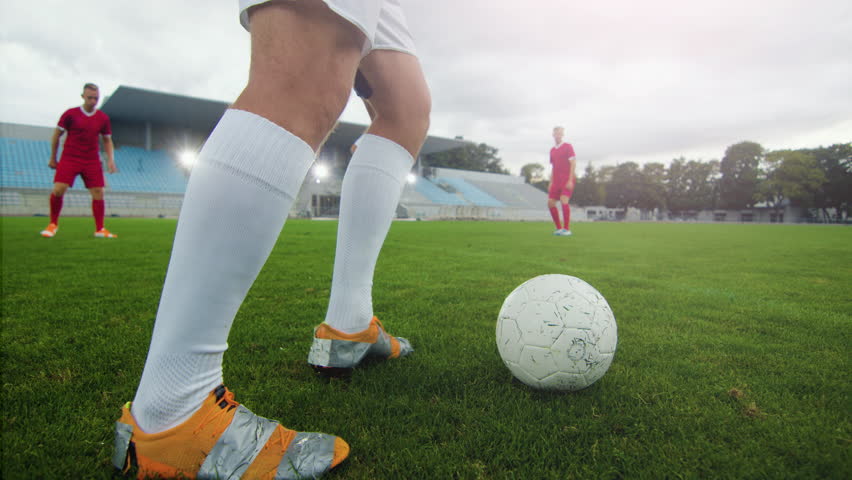 Professional Soccer Player Leads with a Ball, Masterfully Dribbling and Bypassing Sliding Tackles of His Opponents. Two Professional Football Teams Playing. Following Ground Shot. Royalty-Free Stock Footage #1019538256