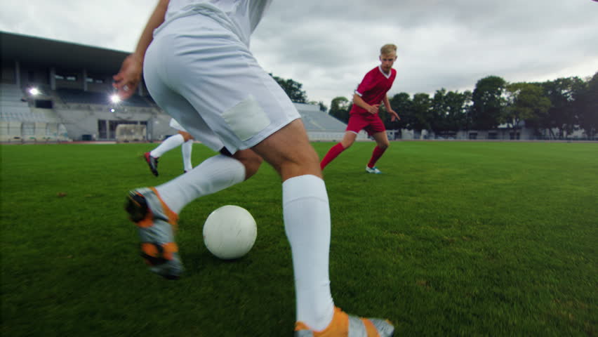 Professional Soccer Player Leads with a Ball, Masterfully Dribbling and Bypassing Sliding Tackles of His Opponents. Two Professional Football Teams Playing. Following Ground Shot. | Shutterstock HD Video #1019538256