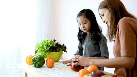 Mom teaching her daughter how to cut and cooking
