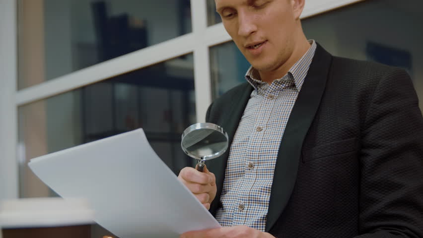 Young business man using magnifying glass for reading financial documents Royalty-Free Stock Footage #1019550883